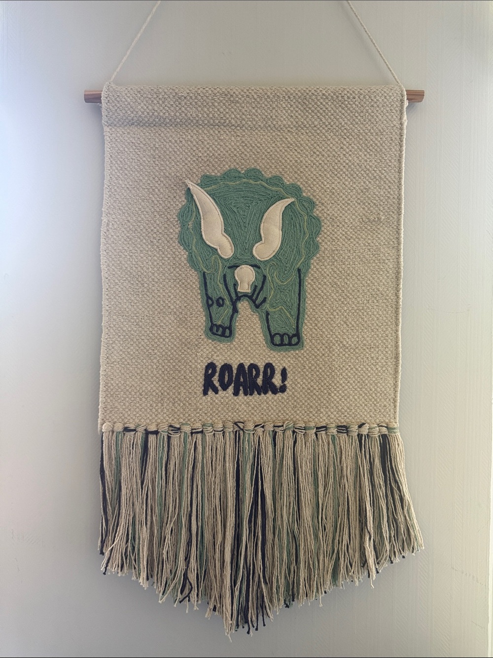 Handwoven Cream Wall Hanging with Green Triceratops Motif Nursery Design